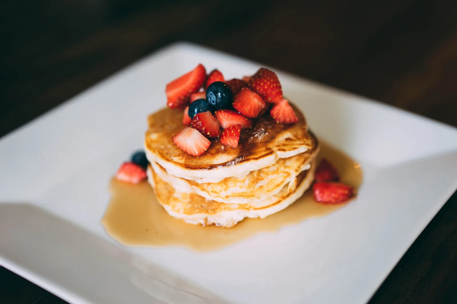A stack of pancakes with strawberries, blueberries and syrup. The photo was not taken at a Norfolk restaurant.