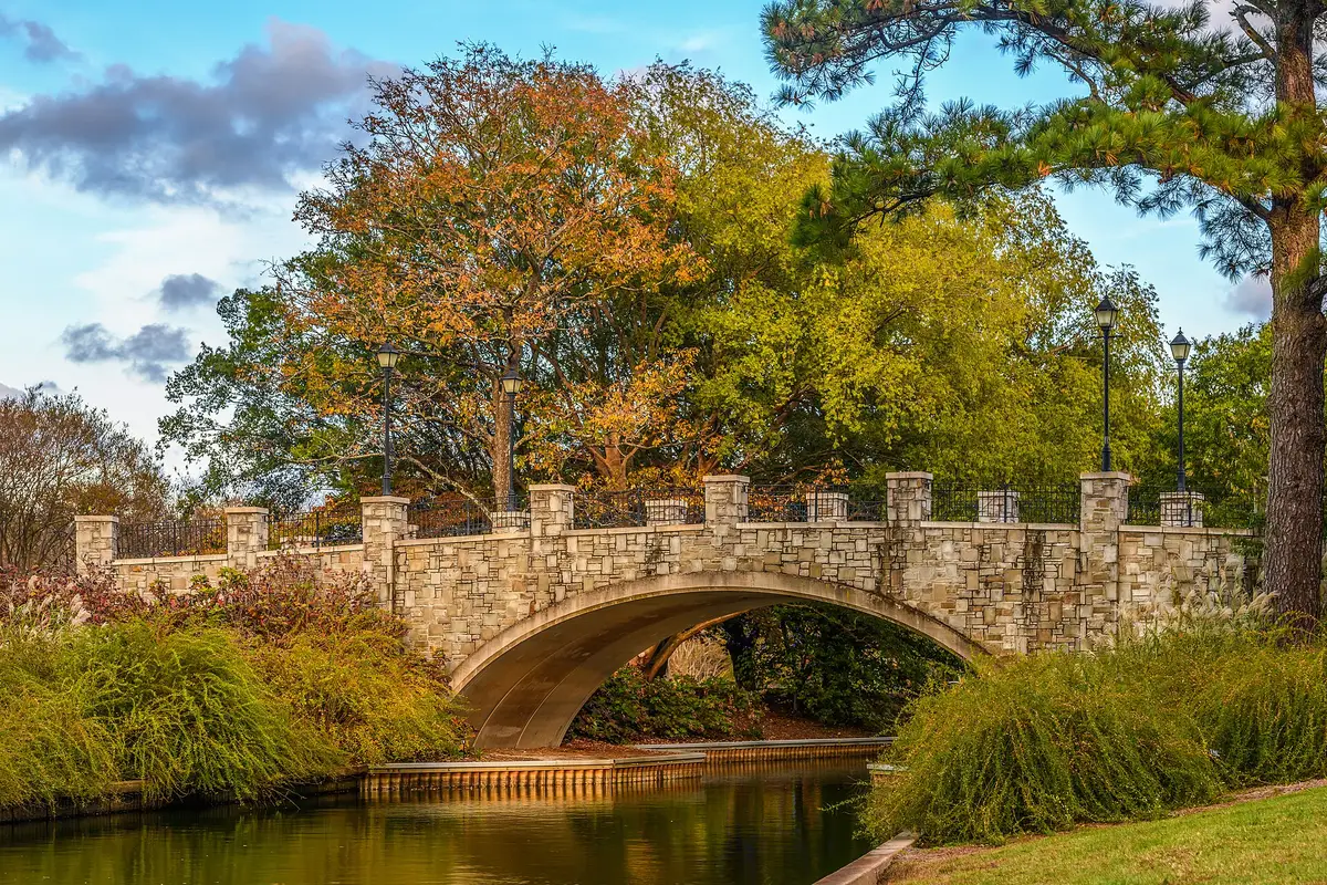 The stone NATO Vista Bridge over a canal by the rose garden at Norfolk Botanical Garden in fall color.