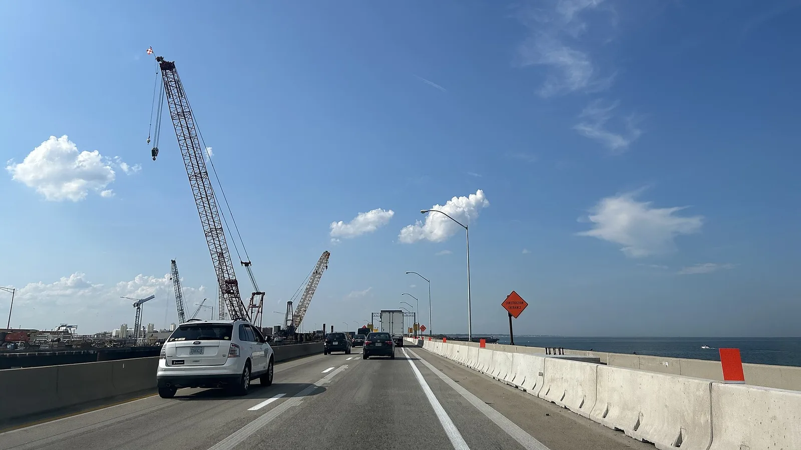 Westbound I-64 traffic passes cranes and work barges for the Hampton Roads Bridge-Tunnel expansion on the trestle leaving Norfolk.