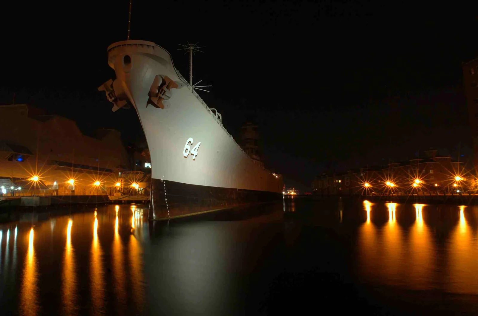 The bow of the Battleship Wisconsin at its berth beside Nauticus in downtown Norfolk at night, shown without its Winterfest lights.